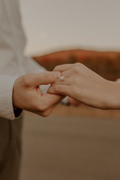 the bride and groom hold hands while holding each other's wedding ring on their finger