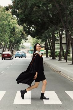 a woman is crossing the street wearing a graduation gown