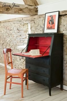 an old fashioned desk and chair in front of a stone wall