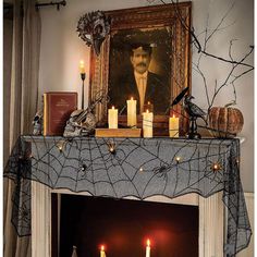 a mantel with candles and pictures on it in front of a fireplace decorated for halloween