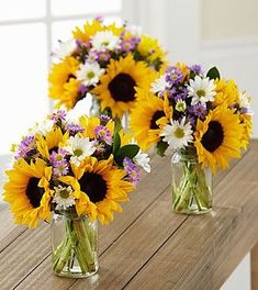 three vases filled with sunflowers and daisies sitting on a wooden table