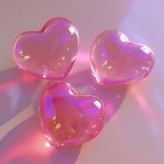 three pink heart shaped soaps sitting on top of a white surface with the light shining through them