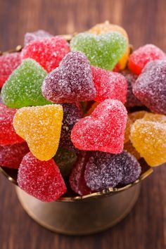 a metal bowl filled with gummy bears on top of a wooden table