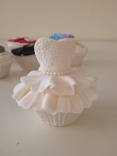 there are cupcakes with white frosting on the top and one is decorated like a dress