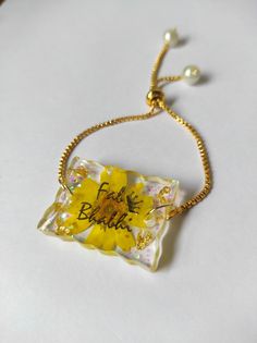 a yellow and white flower necklace with the words love is beautiful written in black on it