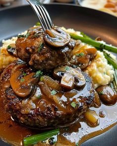 a plate with meat and mushrooms on top of mashed potatoes