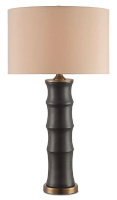 a black lamp with a beige shade on it's base and a white light