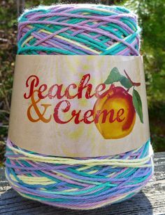 a ball of yarn with the words peaches and creme on it sitting on a wooden table