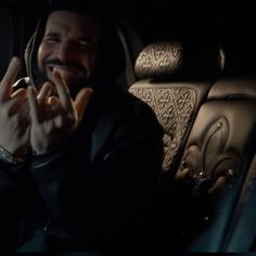 a man sitting in the back seat of a car with his hands up and smiling