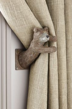 a wooden bear head hanging on the side of a curtain