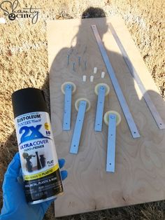 a person holding a spray bottle next to some wooden planks with holes in them