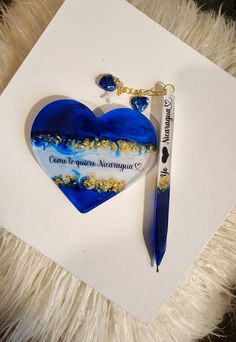 a blue heart shaped keychain sitting on top of a white piece of paper