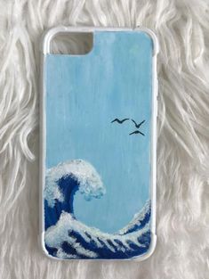 an iphone case with a painting of a wave and birds flying over it on white fur