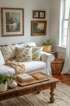 a living room with white couches and pictures on the wall above them, along with potted plants