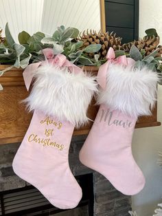 two pink christmas stockings hanging from a mantel