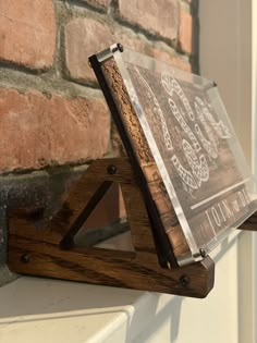 a wooden sign on top of a brick wall next to a white window sill