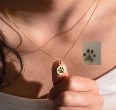 a woman holding a dog's paw print on a necklace