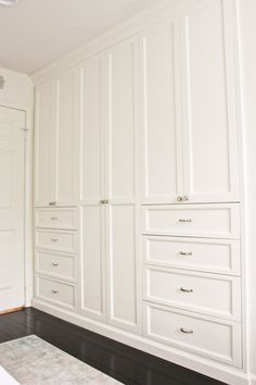 an empty room with white cabinets and drawers