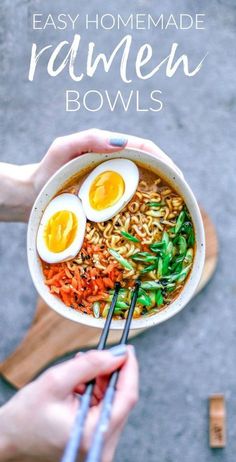 someone holding a bowl of ramen with two boiled eggs in it and chopsticks