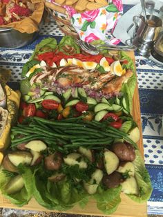 an assortment of vegetables and meats on a cutting board with other food items in the background