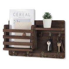 a wooden shelf with keys and key hooks attached to the wall next to a plant