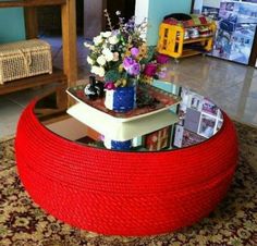 a coffee table made out of rope with flowers on top and magazines in the middle