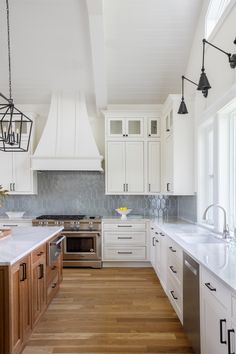 a large kitchen with white cabinets and wood flooring is seen in this image from the front view