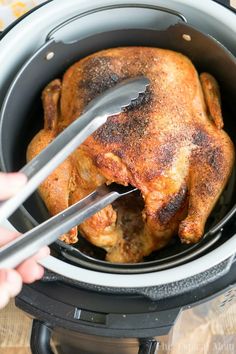 someone is using tongs to cut the chicken into pieces in an air fryer