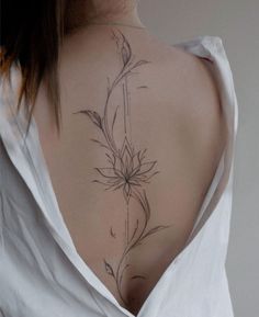 the back of a woman's neck with a flower tattoo on it