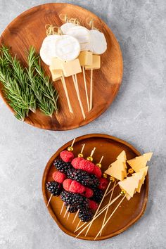 fruit and cheese skewers on wooden plates with rosemary sprigs, pine cones, and blueberries