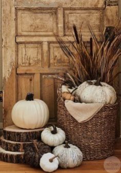 a basket filled with white pumpkins sitting on top of a wooden floor next to a door