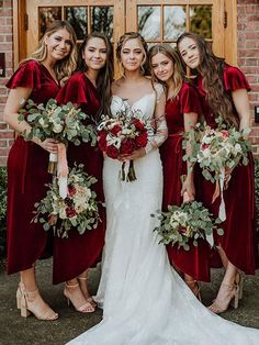 the bride and her bridesmaids are all dressed in red velvet gowns with matching bouquets