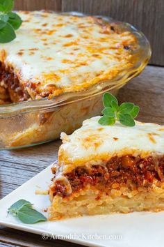 a slice of lasagna casserole on a white plate with a leafy green garnish