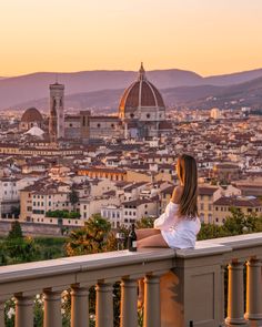 a woman sitting on top of a balcony overlooking a city