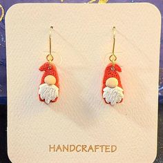 a pair of red and white earrings with an orange bird hanging from it's ear