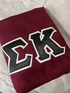 the letter k is painted on top of a maroon and black blanket with white letters