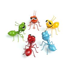 six toy ants with different colored eyes and antennaes on white background, all facing the same direction