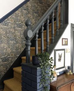 a stair case next to a wall with a painting and potted plant on it