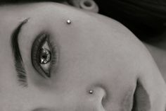 a woman with piercings on her nose and eyes