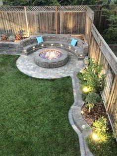 an outdoor fire pit in the middle of a yard with grass and lights around it