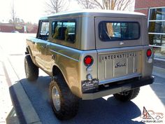 an old jeep is parked on the side of the road in front of a brick building