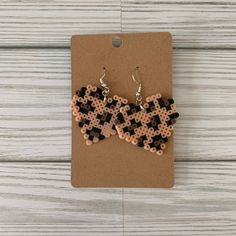 two pieces of black and brown beaded earrings sitting on top of a card