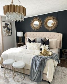 a white bed sitting in a bedroom next to two mirrors and a chandelier