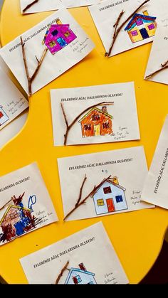 children's artwork is displayed on the table in front of paper cards with houses