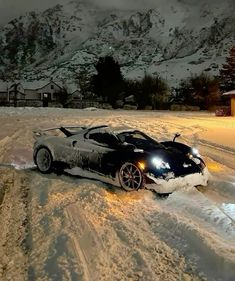 a black sports car driving down a snow covered road