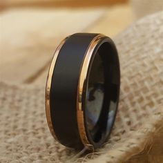 a black and gold wedding ring on top of a piece of fabric