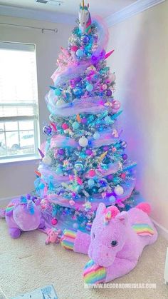 a very colorful christmas tree with an elephant stuffed animal in the middle and other decorations around it