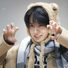 a young man wearing a bear hat and scarf with his hands up in the air