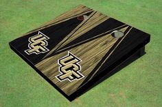 a close up of a cornhole game on the ground with grass in the background