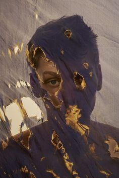 a man's face is covered in gold paint and has his eyes partially obscured by the fabric